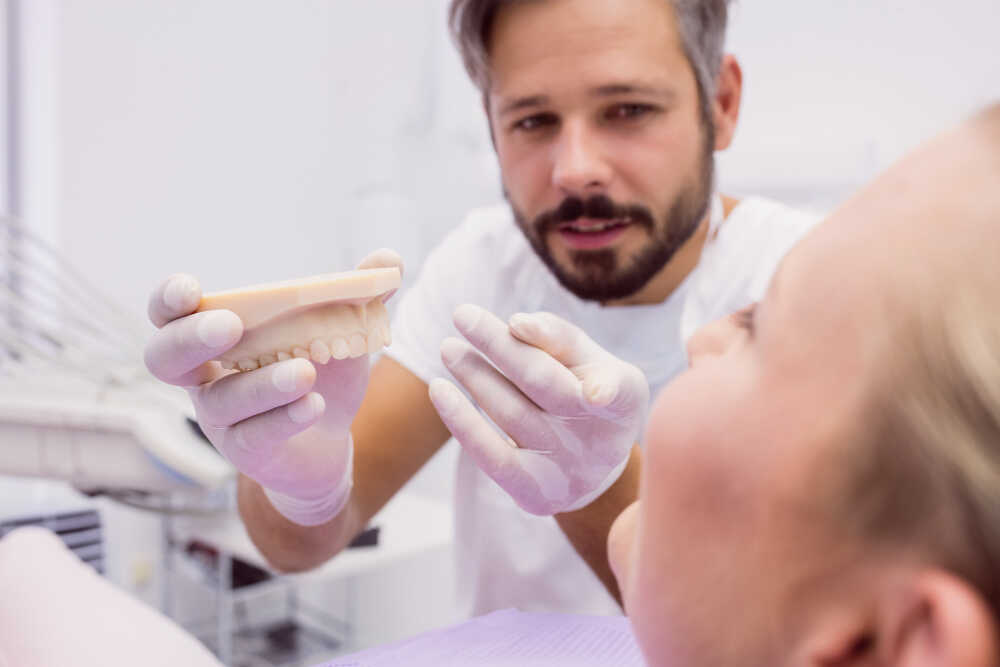 dentysta pokazuje model koron porcelanowych w gabinecie